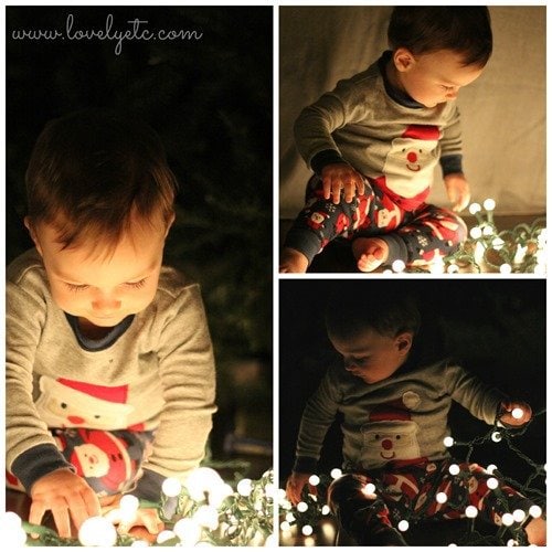 toddler playing with a string of christmas lights on the floor in a dark room.