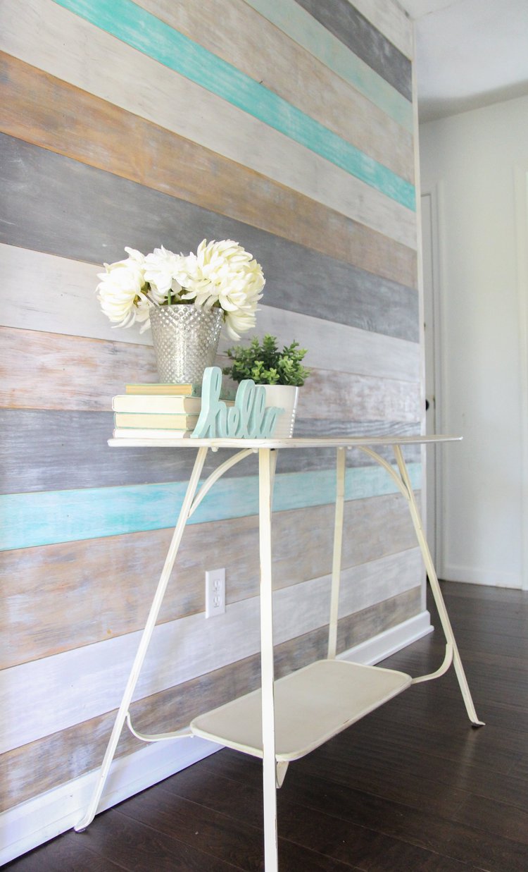 Wood plank wall made from plywood cut into strips and given a weathered look using various colors of paint and stain.