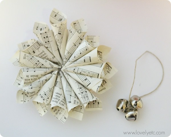 circle of sheet music cones attached to wreath form with three jingle bells on twine next to it.