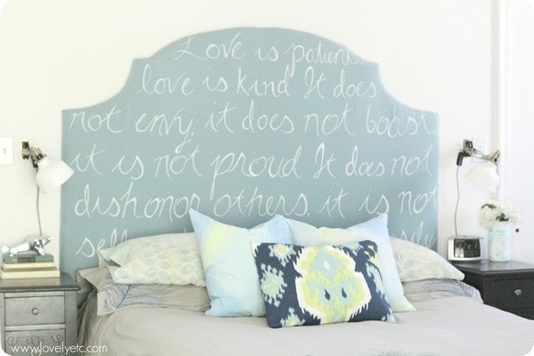 DIY upholstered headboard with text reading Love is patient, love is kind written with paint pen.