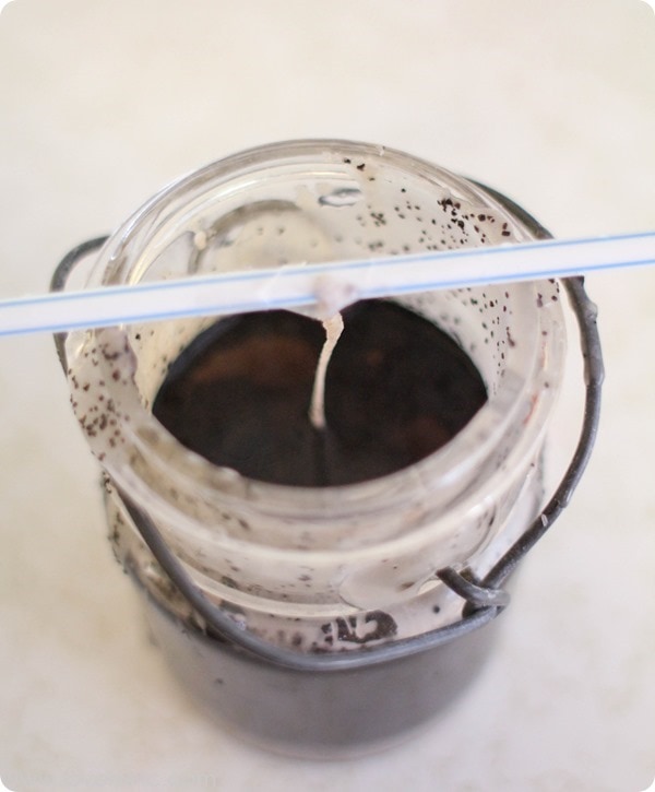 making a jar candle with the wick held upright using a straw.