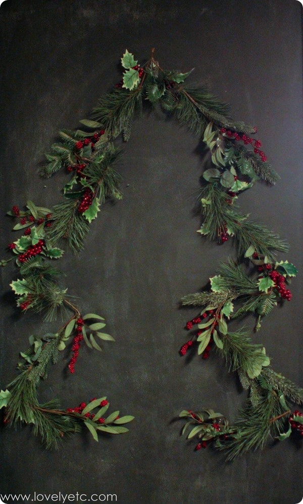 Christmas tree made from garland, hanging on wall.