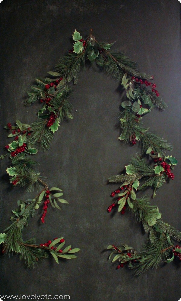 Christmas tree made from garland, hanging on wall.
