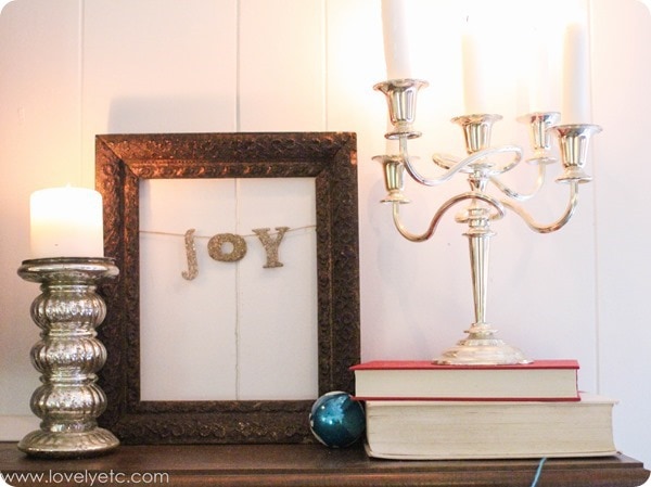 vintage Christmas mantel with silver candlesticks and silver letters spelling joy.