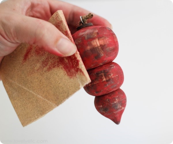 Sanding a painted wooden ornament with sandpaper.