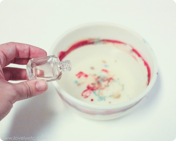 Dropping clear nail polish into a bowl of water to marble ornaments.