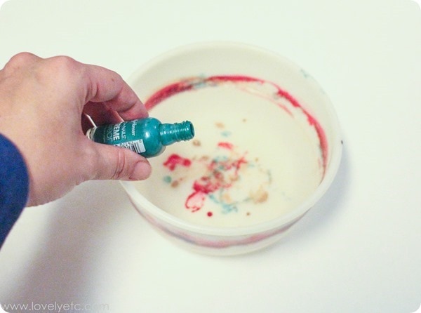 adding nail polish to a bowl of water to marble christmas ornaments.
