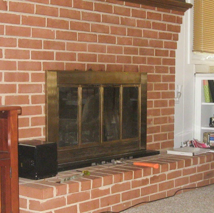 brick fireplace with brass fireplace doors before paint.