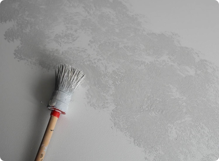 a round paint brush adding gray paint to countertop