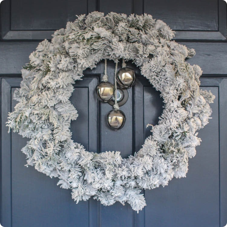 flocked christmas wreath with bells on front door.