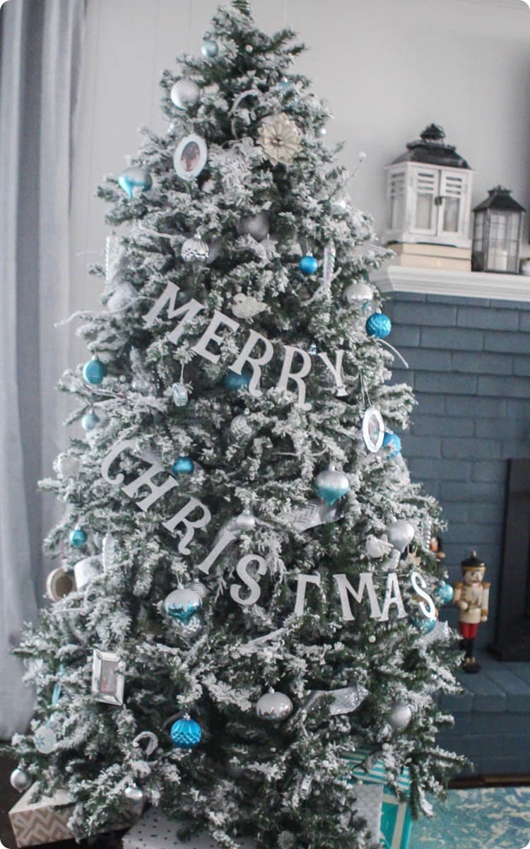 Flocked Christmas tree with blue and white ornaments and Merry Christmas banner.