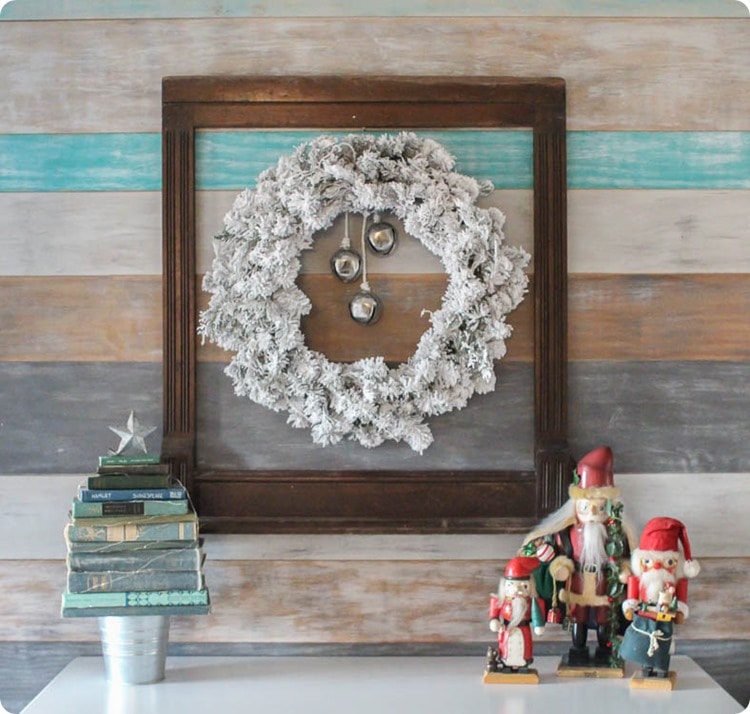 flocked Christmas wreath and vintage frame on wood plank wall.