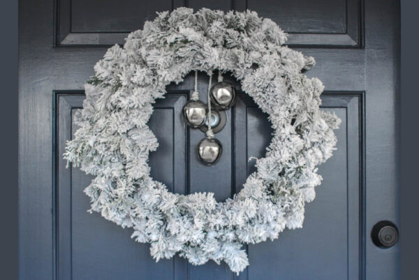 DIY flocked wreath with silver bells hanging on front door.