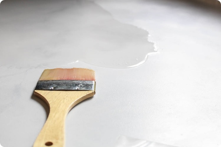 using a paintbrush to spread resin over a painted countertop