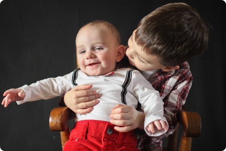 little boy holding baby brother in Christmas photo.