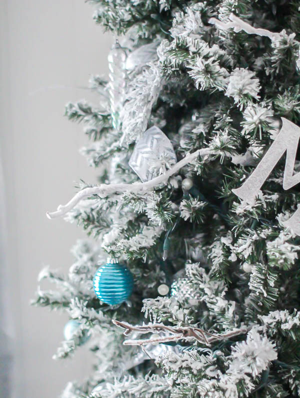 Close up of flocked Christmas tree with flocked branches and vines stuck in.