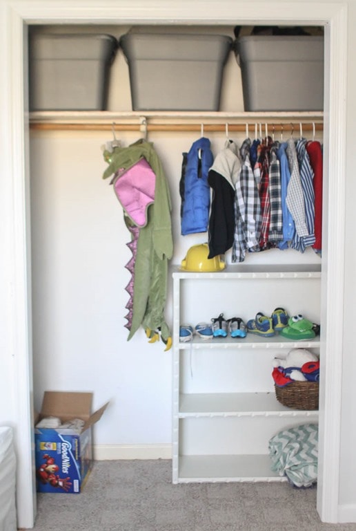 Child's closet before adding diy closet shelves. There is one hanging bar and a bookshelf.