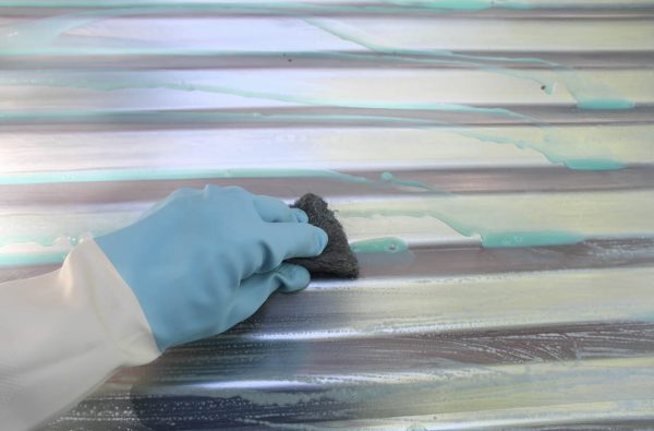 Using steel wool to rub the toilet cleaner all over the metal roofing.