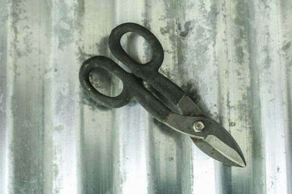 Cutting sheet metal with tin snips.