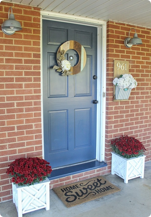  brick ranch with blue front door color with mums in planters
