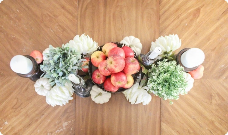 fall centerpiece with apples, pumpkins, flowers, and candles