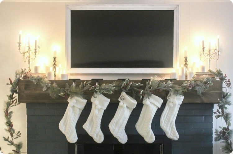 Christmas mantel decorated around tv.