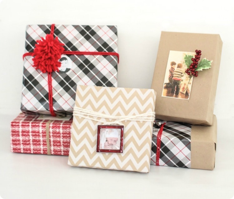 Pile of Christmas gifts wrapped with brown paper and plaid wrapping paper and family photos. 