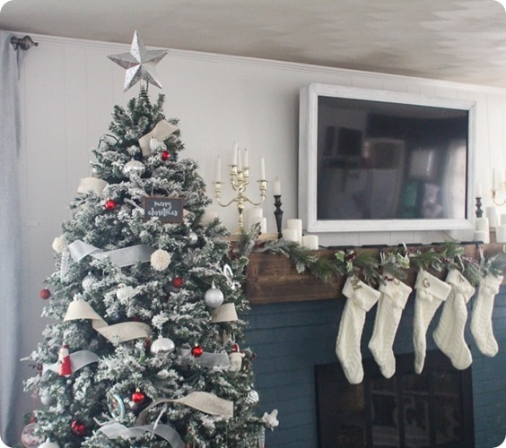 red and white Christmas tree next to fireplace white stockings.