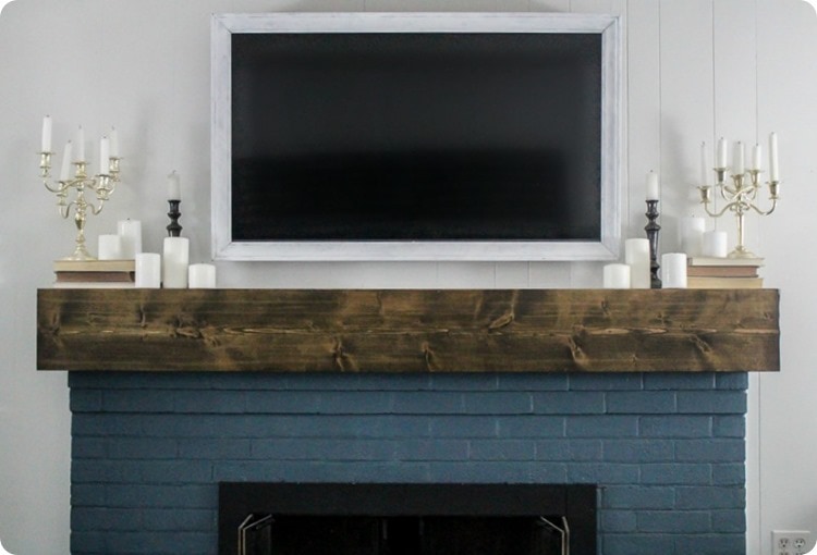 diy wood tv frame hanging over fireplace with diy mantel.