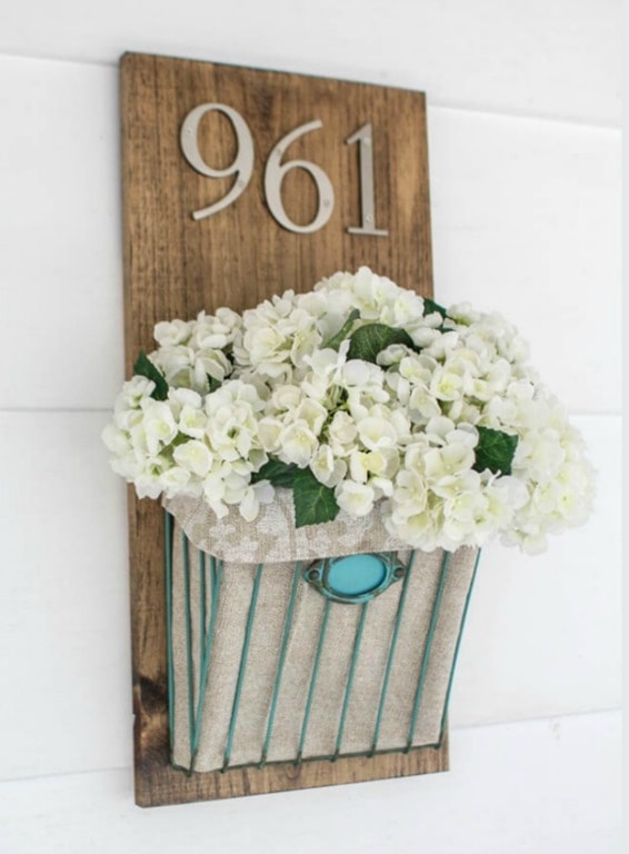 diy house number with a wooden background and a metal basket full of faux flowers