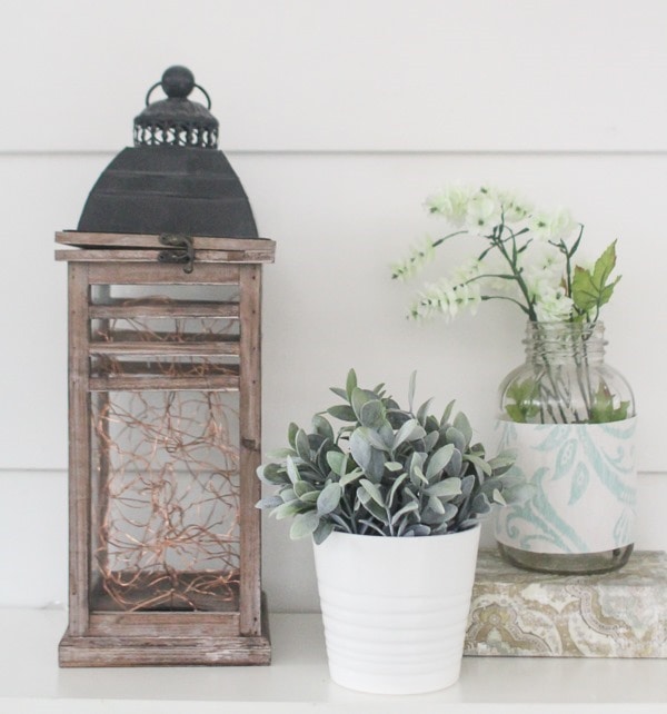 diy fairy light lantern shown on counter with a small plant, book and vase.