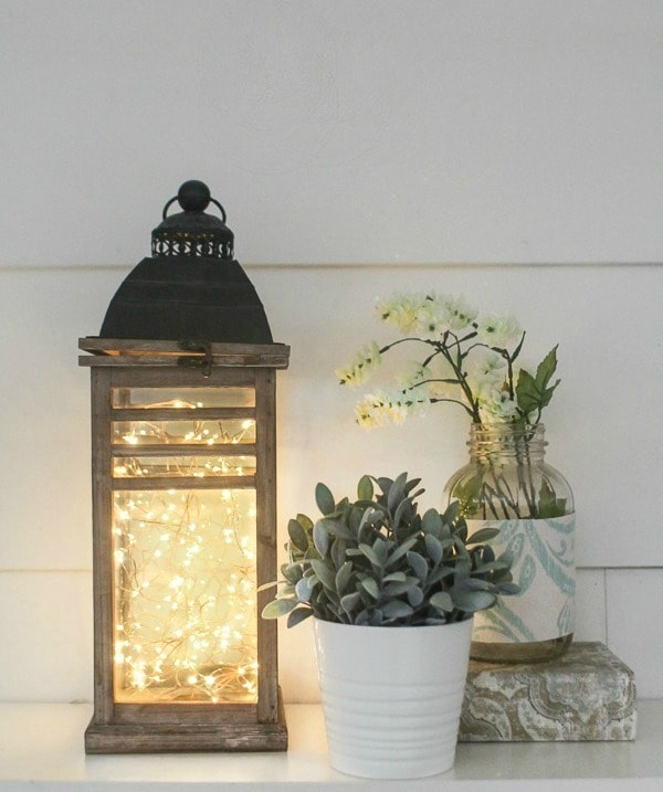 diy fairy light lantern shown on counter with a small plant and vase.