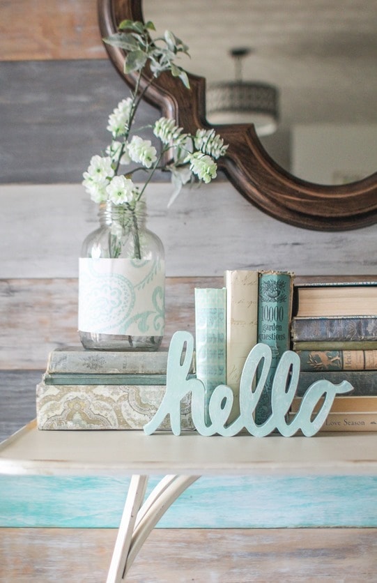 Simple spring entryway decor. Wood wall, quatrefoil mirror, old books, and flowers in mason jars.