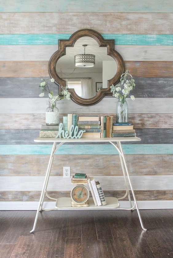 Simple spring entryway decor. Wood wall, quatrefoil mirror, old books, and flowers in mason jars.