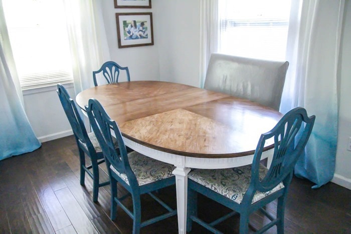 refinished wood dining table with blue dining chairs and gray leather bench.