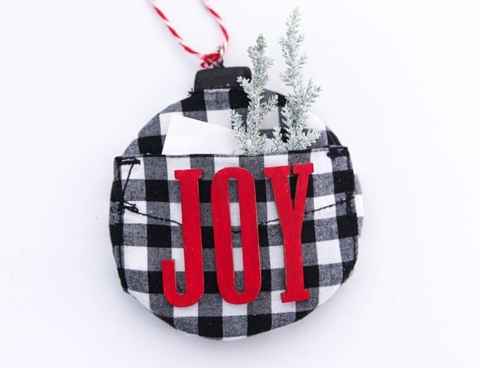 handmade plaid christmas ornament with a note and a few evergreen sprigs tucked in the pocket.