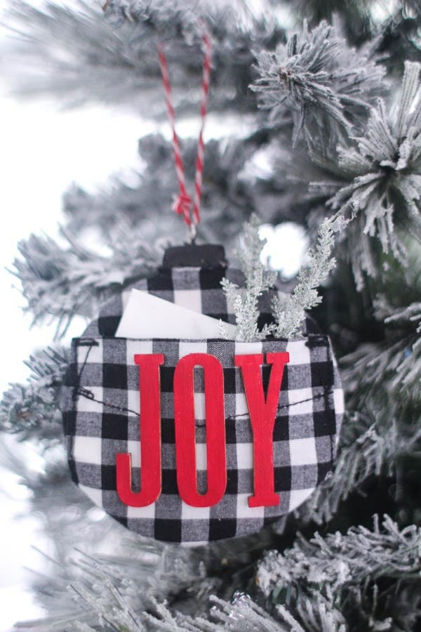 black and white buffalo plaid ornament with red letters that say Joy and a little pocket for holding gift card.