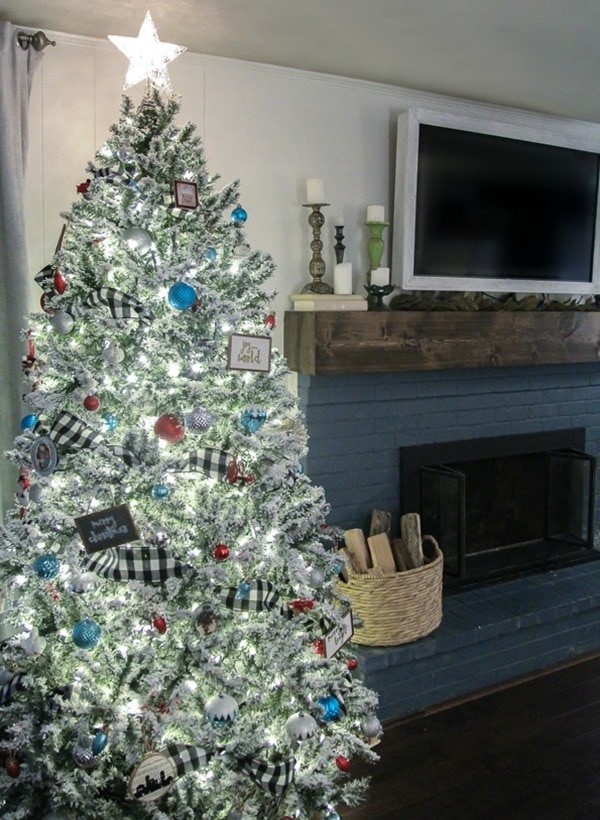 Flocked tree with buffalo plaid ribbon and white lights.