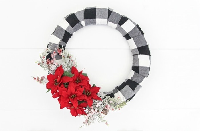 DIY buffalo plaid christmas wreath with Christmas greenery and flowers.