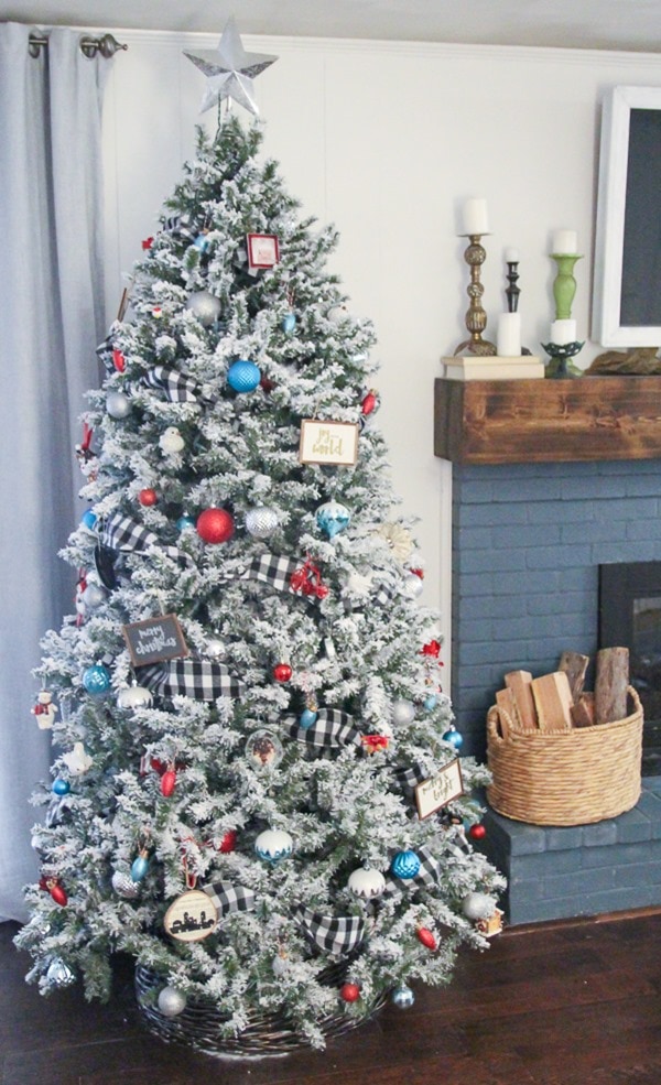 Flocked farmhouse Christmas tree with buffalo plaid ribbon and colorful ornaments.