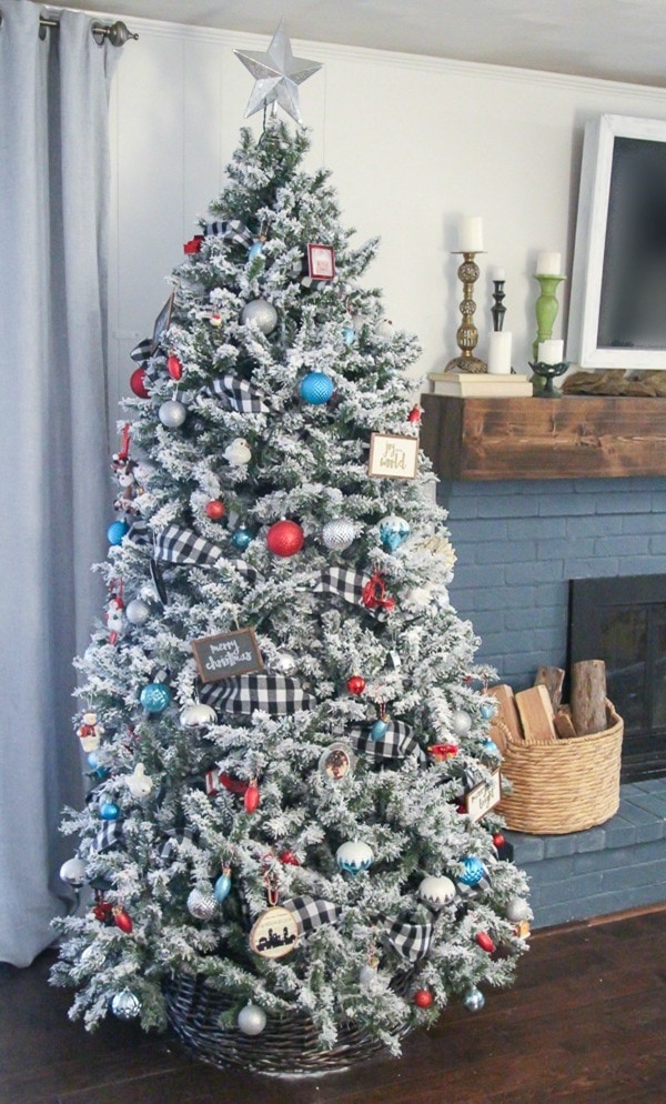 Flocked Christmas tree with buffalo plaid ribbon and red and aqua ornaments.