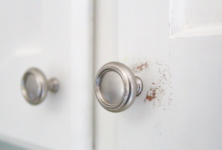 painted white cabinets with chipping paint around hardware