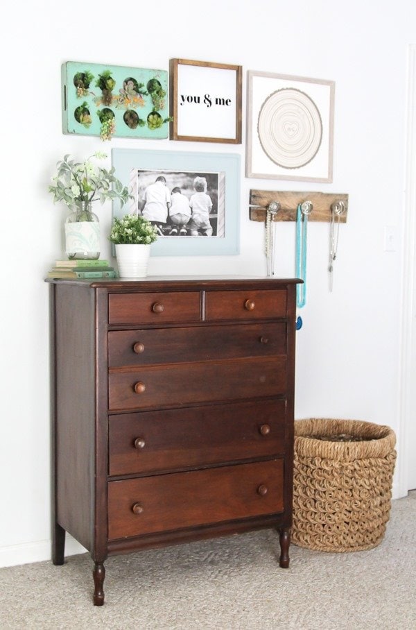 Gallery wall above dresser in bohemian farmhouse space. Green plants and rustic wood add layers of warmth and texture to the space.