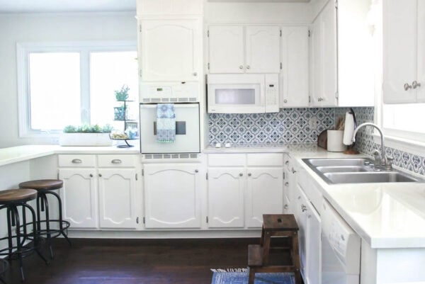 Bright, white kitchen makeover with painted cabinets, painting countertops, stenciling a backsplash.