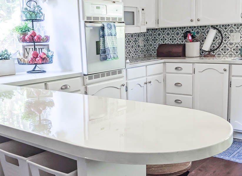 Kitchen updated with painted white countertops, white painted cabinets, and a stenciled backsplash