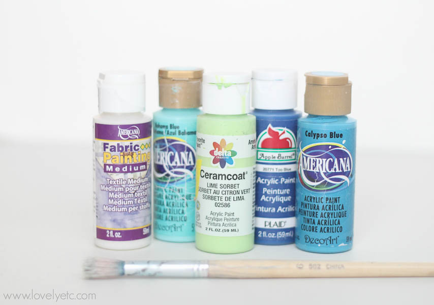 Fabric medium and small acrylic craft paints with a paintbrush.