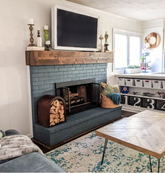 Navy fireplace with chunky DIY mantel and upcycled firewood holder. This whole room is full of DIY and upcycled projects.