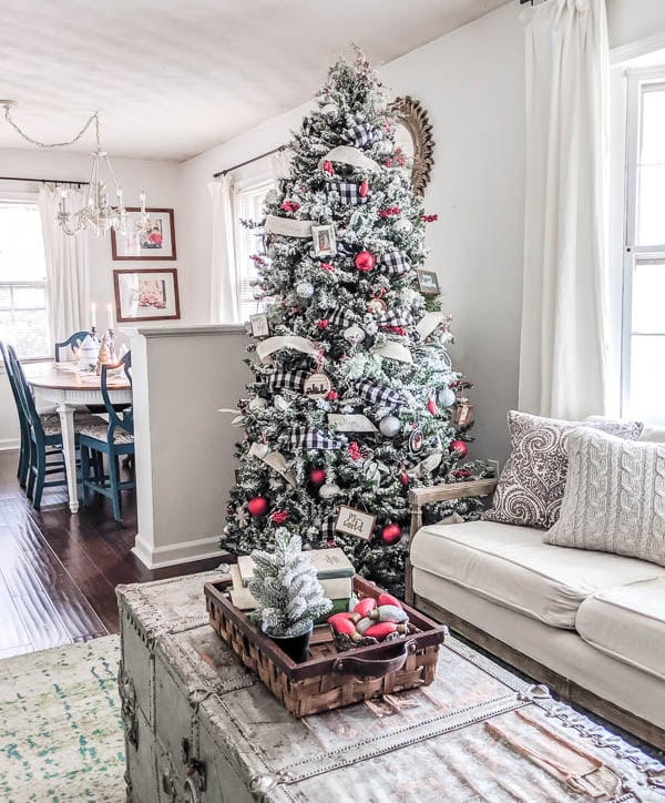 Flocked Christmas tree decorated with buffalo plaid ribbon, linen ribbon, and red and white ornaments.