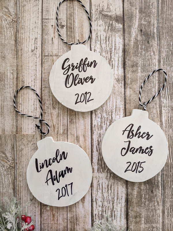 Three DIY Christmas ornaments with names and years written on them.