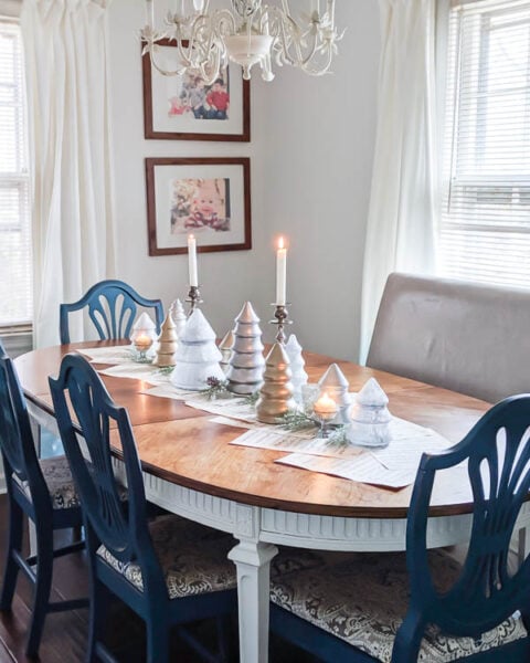 Inexpensive DIY Christmas centerpiece made from painted Christmas tree shaped jars, old sheet music, and candlesticks.